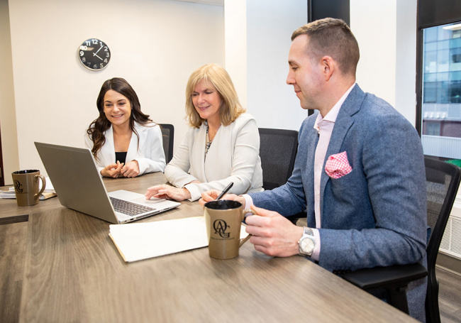 Auditor General, Kim Adair, consulting with diverse coworkers in office.