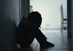 Student sitting on the floor in a darkened hallway 